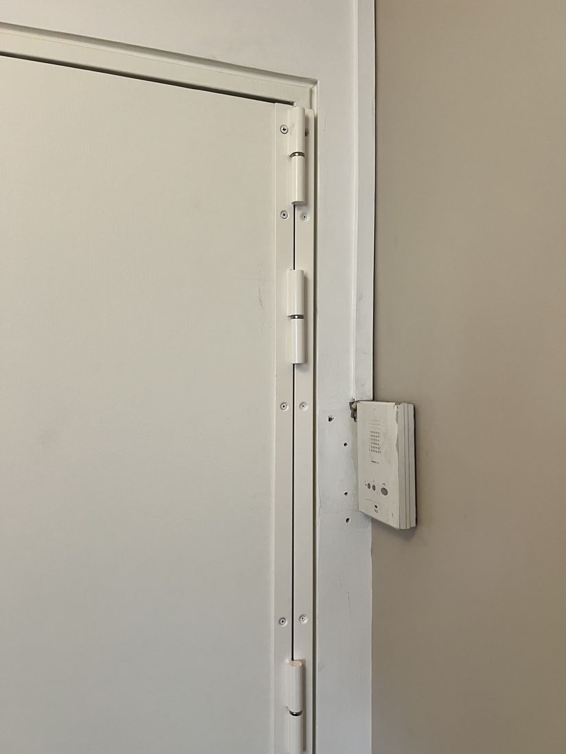 Barre de pivot blanche anti-dégondage posée sur une porte palière à Groslay